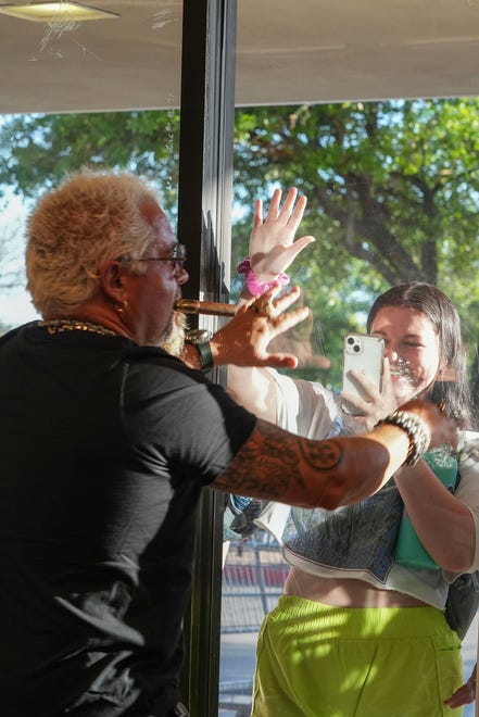 Guy Fieri says hello to a fan, Holly Hundsdorfer, through the window at Twins Liquor at the Hancock Center on Thursday, March 28, 2024. Fieri came to Texas in support of his and Sammy Hagar’s Santo Spirits brand.