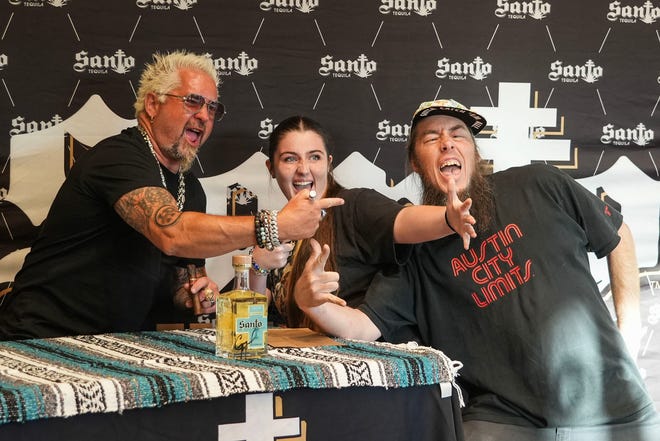 Guy Fieri takes a photo with Savannah and Austin Doerr at Twins Liquor at the Hancock Center on Thursday, March 28, 2024. Fieri came to Texas in support of his and Sammy Hagar’s Santo Spirits brand.