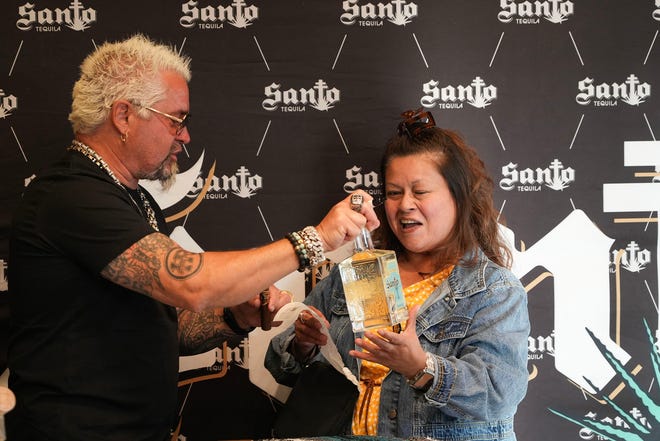 Rachel Rodriguez smiles as she gets her bottle of tequila signed by Guy Fieri at Twins Liquor at the Hancock Center on Thursday, March 28, 2024. Fieri came to Texas in support of his and Sammy Hagar’s Santo Spirits brand.